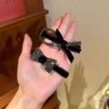 Set of two black velvet bow hair clips with dark grey rhinestones in a hand view - 1+2 Black Criss-cross & Bow (2pcs Set)