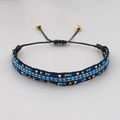 Handgewebtes Perlenarmband mit blau-weißen Wellenmustern und verstellbarem Kordelzug - Mehrfarbig (Blau Weiß Schwarz Gold)