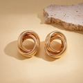 Detail of gold geometric multi-loop twisted knot earrings on a textured stone surface - Gold