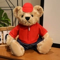 Orsetto di peluche con felpa rossa e cappellino su superficie di legno - Set con Zirconia Rossa