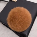 Gros plan d'un pompon en fourrure marron dense sur la surface d'un sac à main en cuir noir - Style Bouton Pression 14CM / Kaki