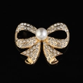 Elegante spilla a fiocco dorata con cristalli scintillanti e perla bianca su nero - Stile B215