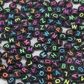 Macro shot of 4x7mm black acrylic letter beads with colorful engraving for DIY crafts - Black & Neon Letters