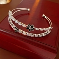 Nahaufnahme des zweilagigen Silberarmbands mit Blumen und Zirkonia auf Schmuckkästchen - Doppelschichtiger offener Stil / Silber Schwarz Blume