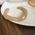 Detail of irregular acrylic cuff bracelet with beige marble texture on ceramic tray - Beige Marble
