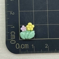 Close-up of mini resin flower charms in yellow and pink on a metric scale cutting mat - Green Leaf Purple Yellow Flower