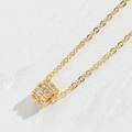 Dettaglio macro del ciondolo a cilindro dorato con zirconi su una catena sottile - Zircone Pieno Cilindrico (Oro)