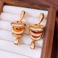 Macro shot of gold tiered circular discs and teardrop pendant earrings in a wooden box - Gold
