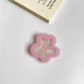 Pink flower-shaped cell phone socket grip on white desk background for handheld support - Pink