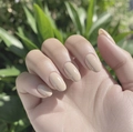 Elegant nude apricot almond-shaped press-on nails shown against a natural green background - Nude Apricot Oval (CW516)