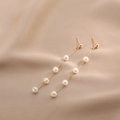 Elegant long gold chain earrings with five white pearls on luxury champagne silk fabric - Gold