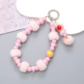 Pink beaded mobile phone wrist strap with plush pompom and fruit charms on grey background - Pink Pompom Pendant Style (K2667)