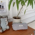 Close-up of light grey corduroy pencil case with green zipper and brand label on desk - Gray