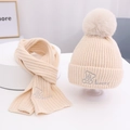 Detail von beige gestricktem Mütze und Schal Set mit Bommel und Bären-Stickerei - Gebrochenes Weiß