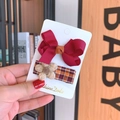 Gros plan d'un nœud bordeaux et d'une barrette à fleurs en tissu écossais pour enfant - Bordeaux