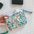 Detailed shot of floral cotton mini pouch with zipper tassel holding a small skincare tube - Beige With Blue Orange Flower