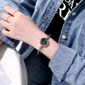 Close-up of minimalist quartz watch with black dial and silver mesh band on woman's wrist - JSK Roman Numerals Silver Band Black Dial