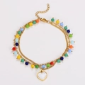 Detalle de pulsera de doble cadena dorada con cuentas de colores y colgante de corazón - Pulsera