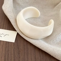 Close-up of wide cream acrylic resin cuff bracelet with a wrinkled geometric design on linen - White - Pleated Open