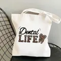 White canvas tote bag featuring Dental LIFE leopard print text and tooth pattern detail - C11 Dental Life Leopard