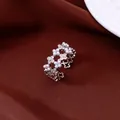 Detailed close-up of adjustable silver flower ring with pearls and zircons on red silk - Silver