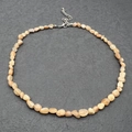 Detailed macro of irregular natural orange quartz stone necklace with silver lobster clasp - Sunstone