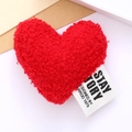 Detail of red plush heart accessory with white woven label showing black printed text - Red
