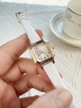 Detailed shot of a women's square rose gold watch with a white textured leather strap - White