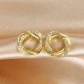 Close-up of gold twisted knot earrings with cubic zirconia on champagne silk background - Gold