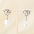 Detail of silver heart-shaped knot earrings with hanging white baroque pearls on display - Steel Heart Knot (KE115980-GC)