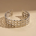 Macro shot of silver wide-open cuff bracelet with hollow geometric patterns and shadows - Silver