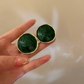 Macro shot of gold-edged round green marble stud earrings held between fingers - 2 Silver Needles #round