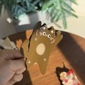 Gros plan d'une pince à cheveux chat en acétate marron tenue sur une table en bois - Chat Brun Levanta