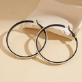 Detailopname van grote ronde oorbellen met zwart-wit contrast en letteropdruk - Witte Ring / Wit