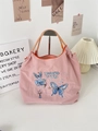 Detail of pink embroidered tote bag featuring blue butterfly and braided handle straps - Floral Butterfly Pink