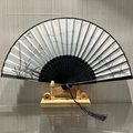 Traditional Chinese folding fan with black ink bamboo pattern and elegant silk tassel - Rolling Green Mountains