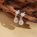 Detalle de pendientes florales plateados con perlas blancas en una rama de madera real - Pendientes (Pin de plata 925 - Plata)