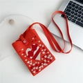Close-up of red knit phone bag with white heart patterns on a white desk - Orange Red Hearts