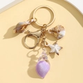 Detailed macro view of gold metal keychain with starfish and purple glitter conch charms - Solid Purple