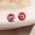 Detailed macro view of gold plated evil eye stud earrings with zircon and colorful enamel - Transparent Red Style (44229)