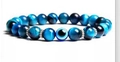 Blue tiger eye beaded bracelet with an evil eye charm and silver-colored spacers - Peacock Blue Tiger Eye