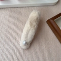 Vista dettagliata del fermaglio in peluche beige con perla su sfondo di velluto - Stile Perla / Beige