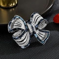 Vue macro d'une broche nœud argentée avec pierres bleu foncé et pavé de cristaux - Bleu marine