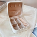 Detailed layout of portable jewelry box with necklace hooks and ring slots in beige - White