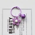 Detail of purple flower and bell keychain on a minimalist white art background card - Purple