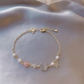 Détail d'un bracelet doré de luxe avec perles et breloques lune et étoile sur satin gris - 33# Style Or Étoile Lune Perle Quartz Rose