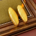 Macro detail of gold oval earrings with textured stripes on a vintage wooden frame - Oval / Gold