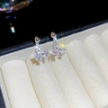 Dettaglio di orecchini a fiocco in argento con zirconi in una scatola per gioielli beige - Argento