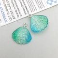 Macro shot of seashell-shaped resin charms with rainbow glitter and silver rings - 1 Piece/Pack (20x22mm)