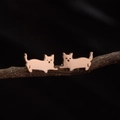 Vista macro de los pendientes de gato en oro rosa sobre una rama de madera rústica - Oro rosa